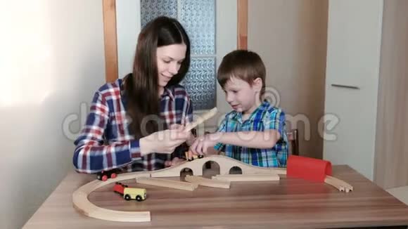 一起玩妈妈和儿子正在建造一条木铁路桌子旁坐着隧道视频的预览图
