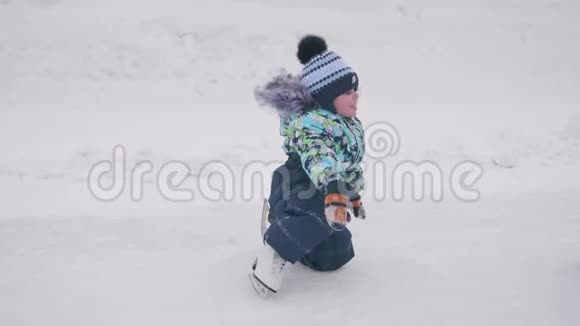 幼儿在溜冰鞋上的第一步滑雪板上的男孩摔倒了站不起来积极的生活方式视频的预览图
