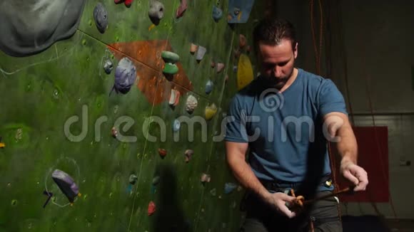 一名登山者在攀爬墙的背景下准备设备登山用编织结慢慢视频的预览图
