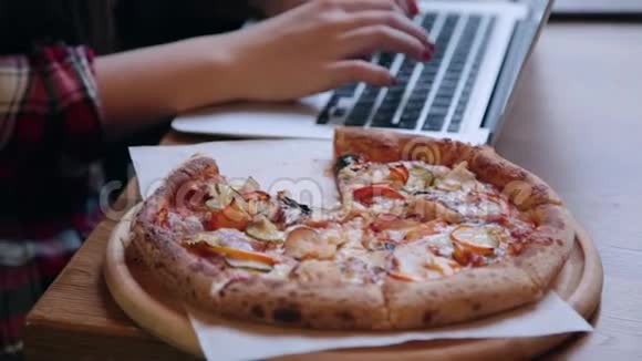 漂亮迷人的商务女性在咖啡馆里的笔记本电脑后面工作桌子上有披萨视频的预览图