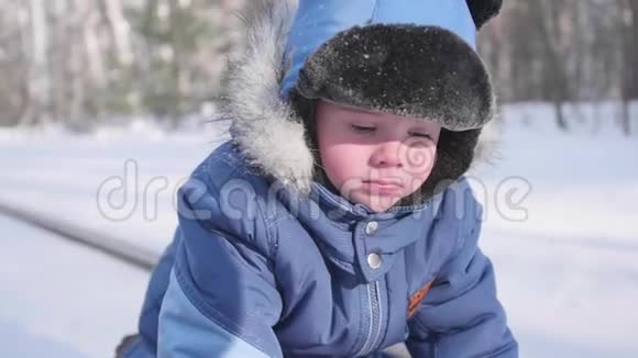 一个小孩子在冬季公园散步晴朗的霜天新鲜空气中的乐趣和游戏视频的预览图