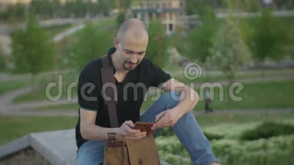 夏日城市公园里迷人的男性西迪亚用智能手机上网视频的预览图