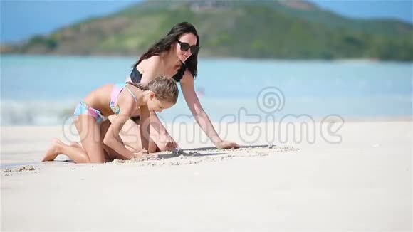 母亲和她的小女儿享受加勒比海海滩度假一家人在热带海滩玩沙视频的预览图
