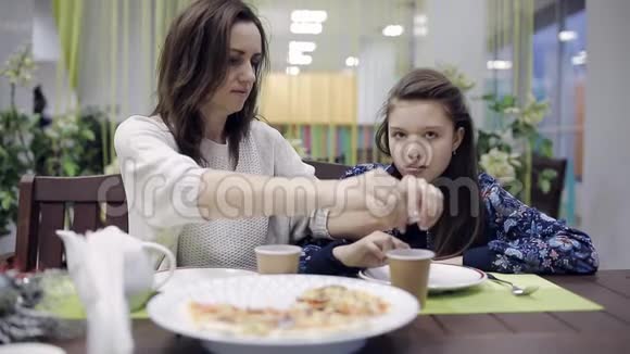 妈妈和女儿在咖啡馆里吃披萨和茶在披萨店吃晚饭快餐中不健康的食物视频的预览图