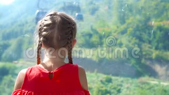 可爱快乐的小女孩在小屋的缆车上在群山的背景下美丽的风景视频的预览图