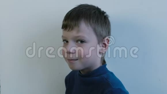穿着蓝色高领毛衣的7岁男孩在灯光背景下转向相机侧视视频的预览图