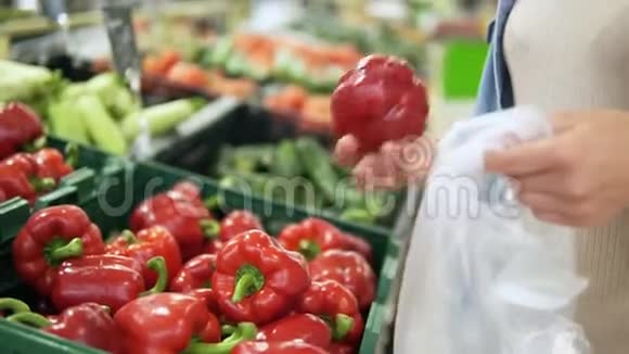 一个女孩手从蔬菜部门的盒子里挑选新鲜的红甜椒的录像杂货店视频的预览图