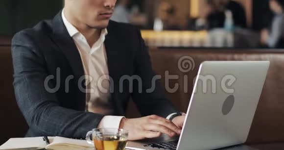 微笑的商人用笔记本电脑坐在咖啡馆的桌子旁视频的预览图