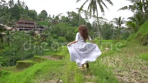 在巴厘岛旅行穿着长裙的女人在米台跑道上奔跑视频的预览图