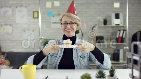 办公室女商人吹一个便士的口哨戴着生日帽无聊的生日概念她举办了一个生日杯视频的预览图