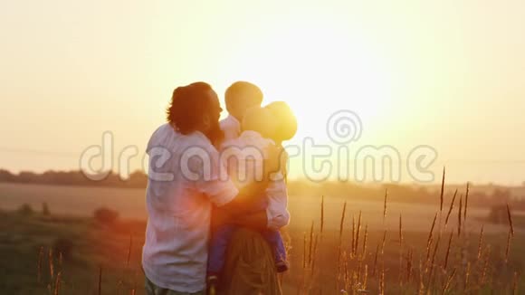 快乐的童年父母在夕阳的照耀下拥抱孩子视频的预览图