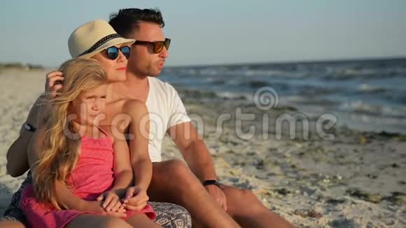 户外幸福家庭与女儿在海滩度假的肖像戴太阳镜的父母微笑视频的预览图