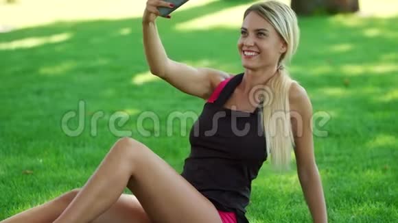 夏日公园的金发女人在手机上自拍视频的预览图