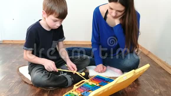 演奏乐器妈妈和儿子坐在地板上的房间里玩木琴视频的预览图