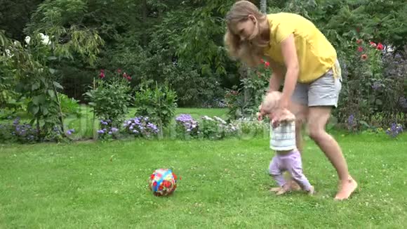 可爱的男婴在绿色草坪上用母亲的支持做第一步接球视频的预览图
