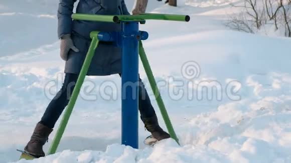在城市的一个冬季公园里特写的女人腿在模拟器上做运动侧视前景视频的预览图