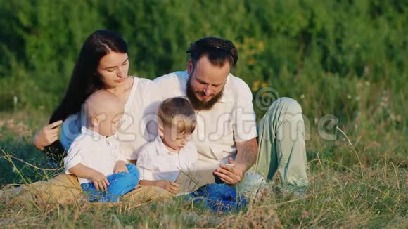 两个小兄弟和他们的父母在一片盛开的草地上玩耍视频的预览图