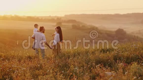 一对年轻有趣的夫妇带着两个年轻的儿子护送着即将离去的太阳走出地平线视频的预览图