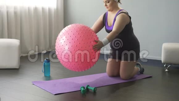超重女士试图训练有趣的尝试躺在大健身球上视频的预览图