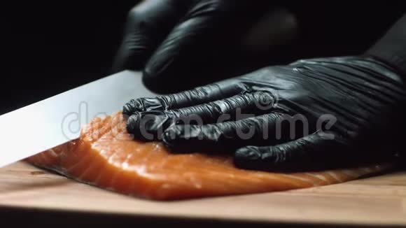 配红色三文鱼的特写厨师专业厨师戴着黑色手套把一块新鲜鲑鱼切成薄片视频的预览图