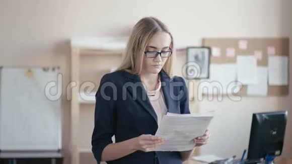 呼叫中心员工在办公室工作一个金发戴眼镜的年轻女孩正站在办公室里手里拿着视频的预览图
