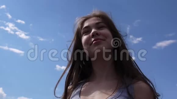在蓝天背景上用风吹毛求疵地勾勒出一幅美丽的少女微笑的肖像视频的预览图