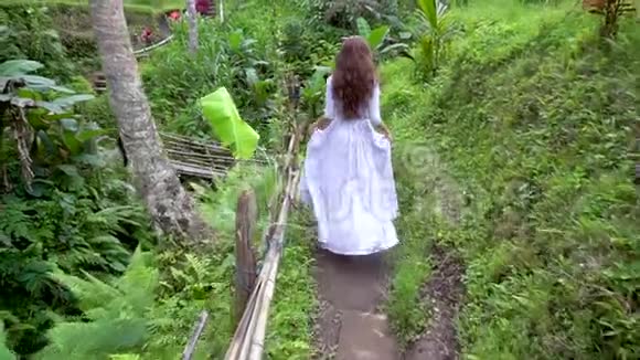 在巴厘岛旅行穿裙子的女人在热带森林公园散步视频的预览图