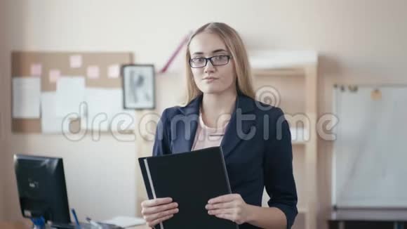 呼叫中心员工在办公室工作一个金发戴眼镜的年轻女孩站在办公室里手里拿着一个视频的预览图