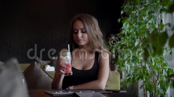可爱的女孩坐在咖啡馆里在室内喝冷饮视频的预览图