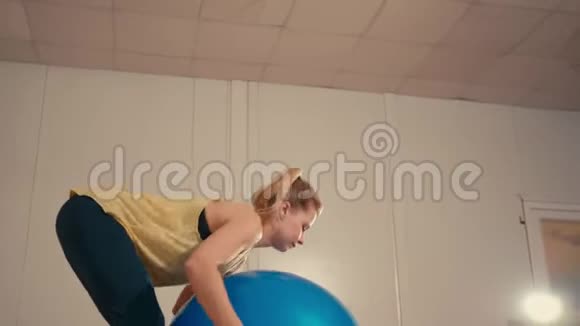 年轻女子在训练场用手中的健身球做蹲视频的预览图