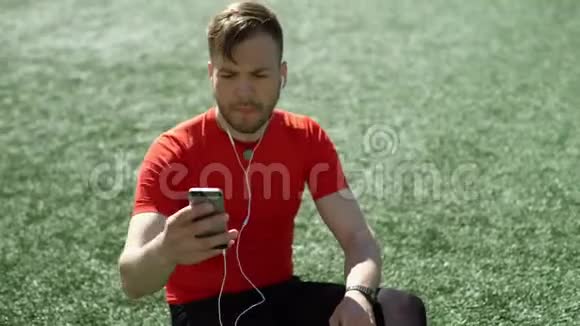 男人听音乐在球场草坪上自拍视频的预览图