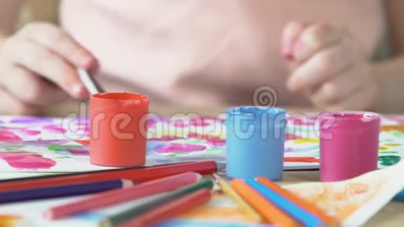 装满丙烯酸颜料和画笔的桌子孩子们在背景中画画视频的预览图