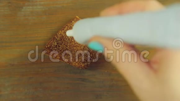 一只手握着一管烹饪颜料在一块巧克力饼干上画出带有黄色颜料的滑稽表情视频的预览图