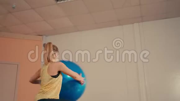 年轻的运动女士在训练场用手中的健身球做蹲视频的预览图
