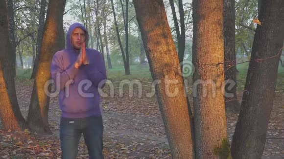 英俊的男人感到寒冷和温暖的手男人在秋天的公园里结冰冷冷的视频的预览图