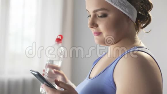 运动女性在智能手机上滚动寻找新的减肥方法视频的预览图
