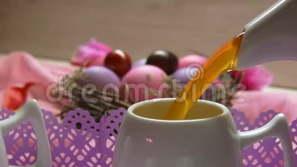 彩色粉红色复活节彩蛋茶倒在杯子里视频的预览图
