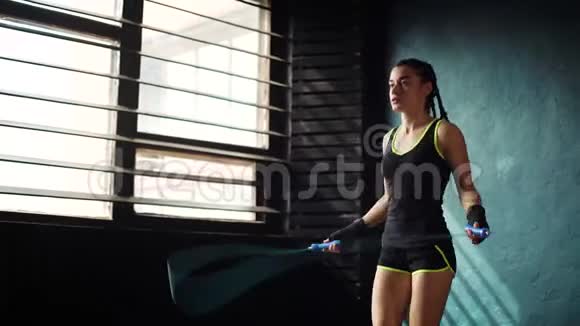年轻有目的严肃的女拳击手裹着绷带手在健身房跳绳视频的预览图