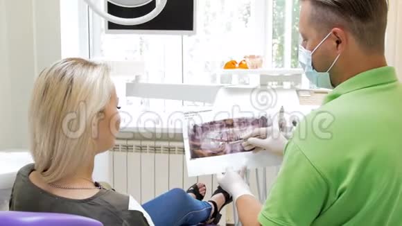 牙科医生用X线口腔图像向病人解释牙齿治疗的4k镜头视频的预览图