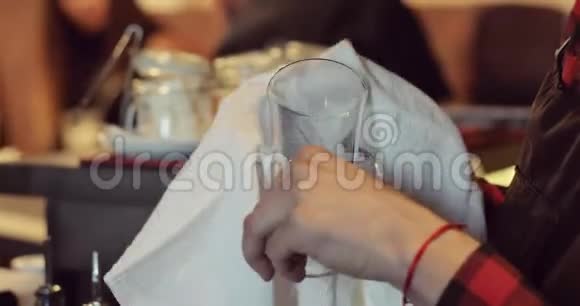 酒吧服务员用白色毛巾擦拭杯子的特写视频的预览图
