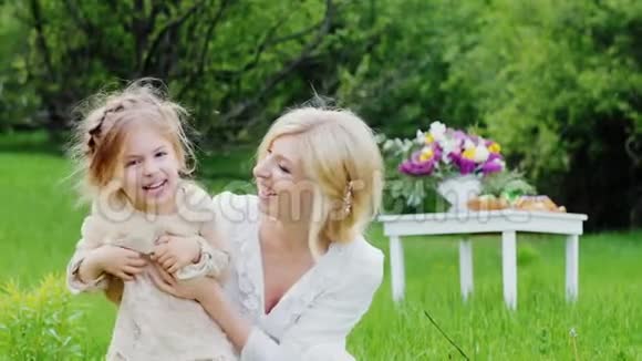 可爱的小女孩穿着时髦的浅色连衣裙在房子的院子里和妈妈玩得很开心视频的预览图
