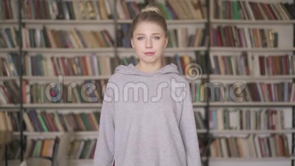 站在书架背景上的年轻女学生画像视频的预览图