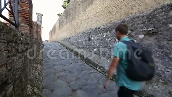 游客沿着庞贝城墙之间狭窄的鹅卵石铺就的街道后景视频的预览图