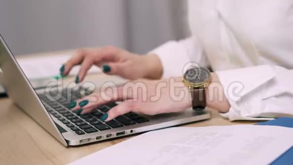 女性手在办公室的笔记本电脑键盘上打字视频的预览图