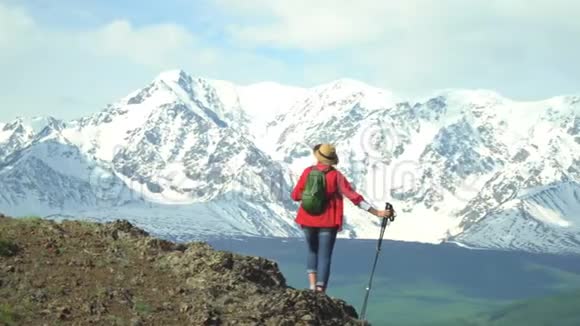 穿红色衬衫背着绿色背包的旅行者在山上花了不少钱看雪山视频的预览图