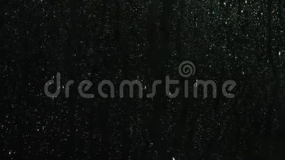 雨滴溅在黑色背景上的玻璃上库存录像雨水背景滴在玻璃上视频的预览图