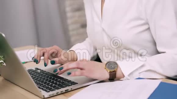 女性手在办公室的笔记本电脑键盘上打字视频的预览图