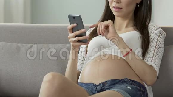 未来的母亲滚动手机屏幕阅读怀孕博客在线咨询视频的预览图