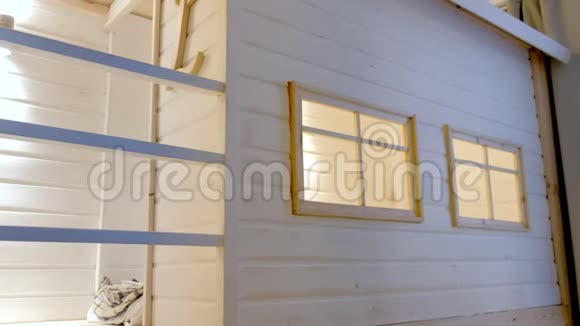 儿童房的木制白色房子里面有窗户和床视频的预览图
