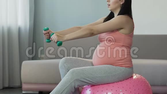 孕妇坐在健身球上用小哑铃锻炼身体健康视频的预览图